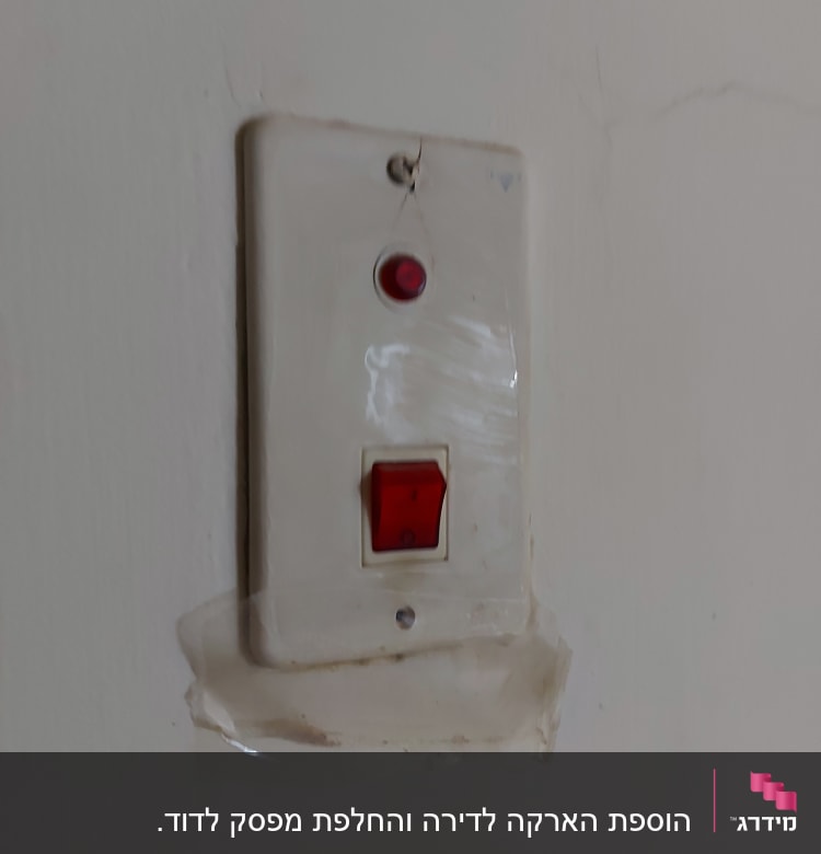 מתג חשמלי עם כפתור אדום וקיר סדוק